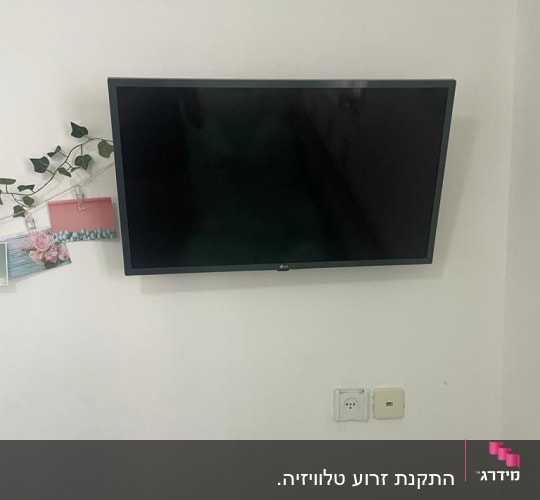 טלוויזיה תלויה על הקיר ליד שקע חשמל